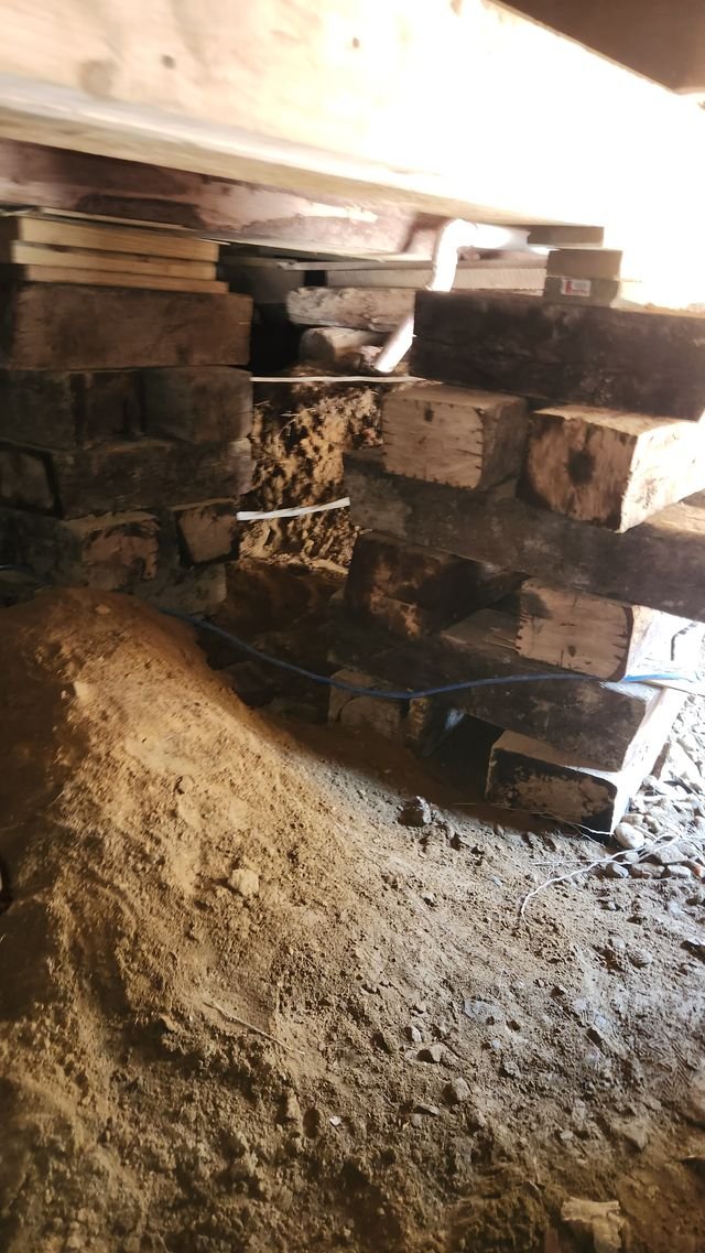 A pile of dug-out dirt beside tall stacks of timber cribbing