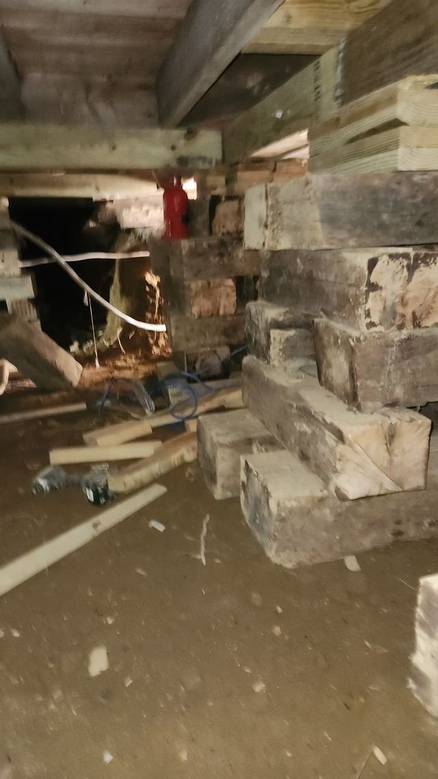 Stacked timber cribbing reaching up to the house beams